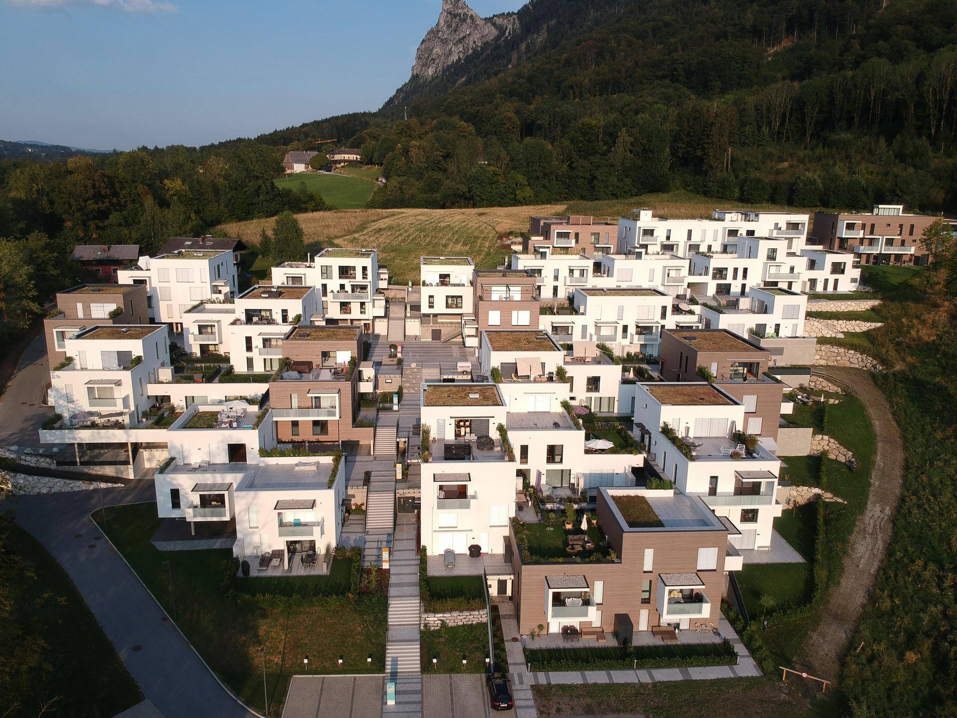 Panoramablick auf die moderne Wohnanlage mit Bergblick, grünen Dächern und Terrassen in naturnaher Lage.