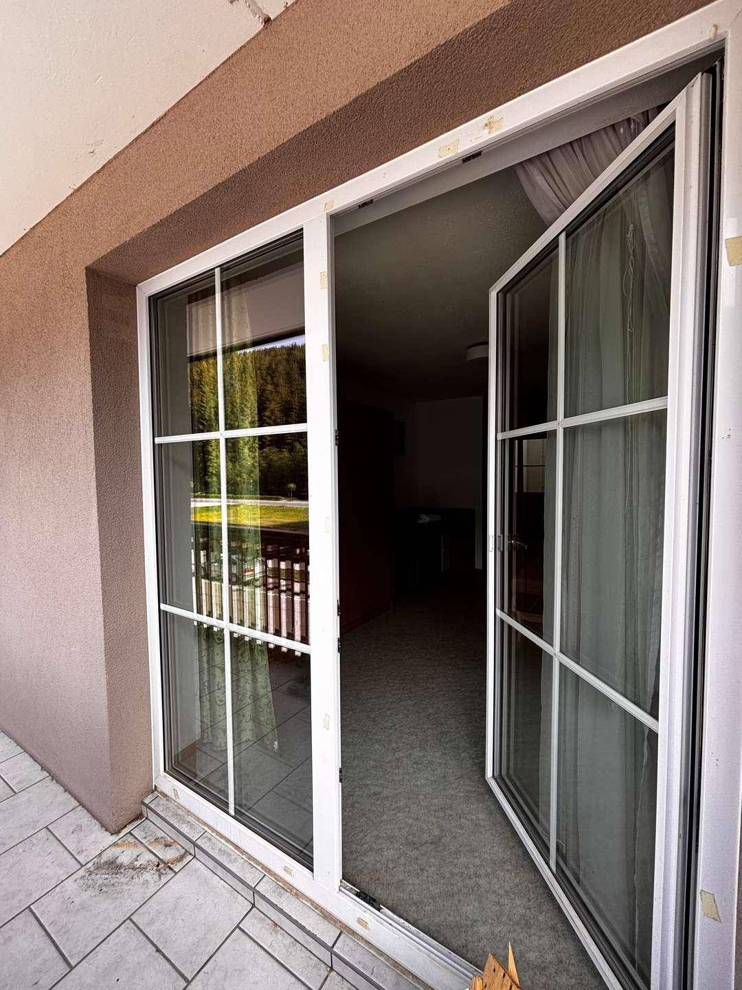 Offene Balkontür führt von der gefliesten Terrasse in den Innenbereich des Apartments.