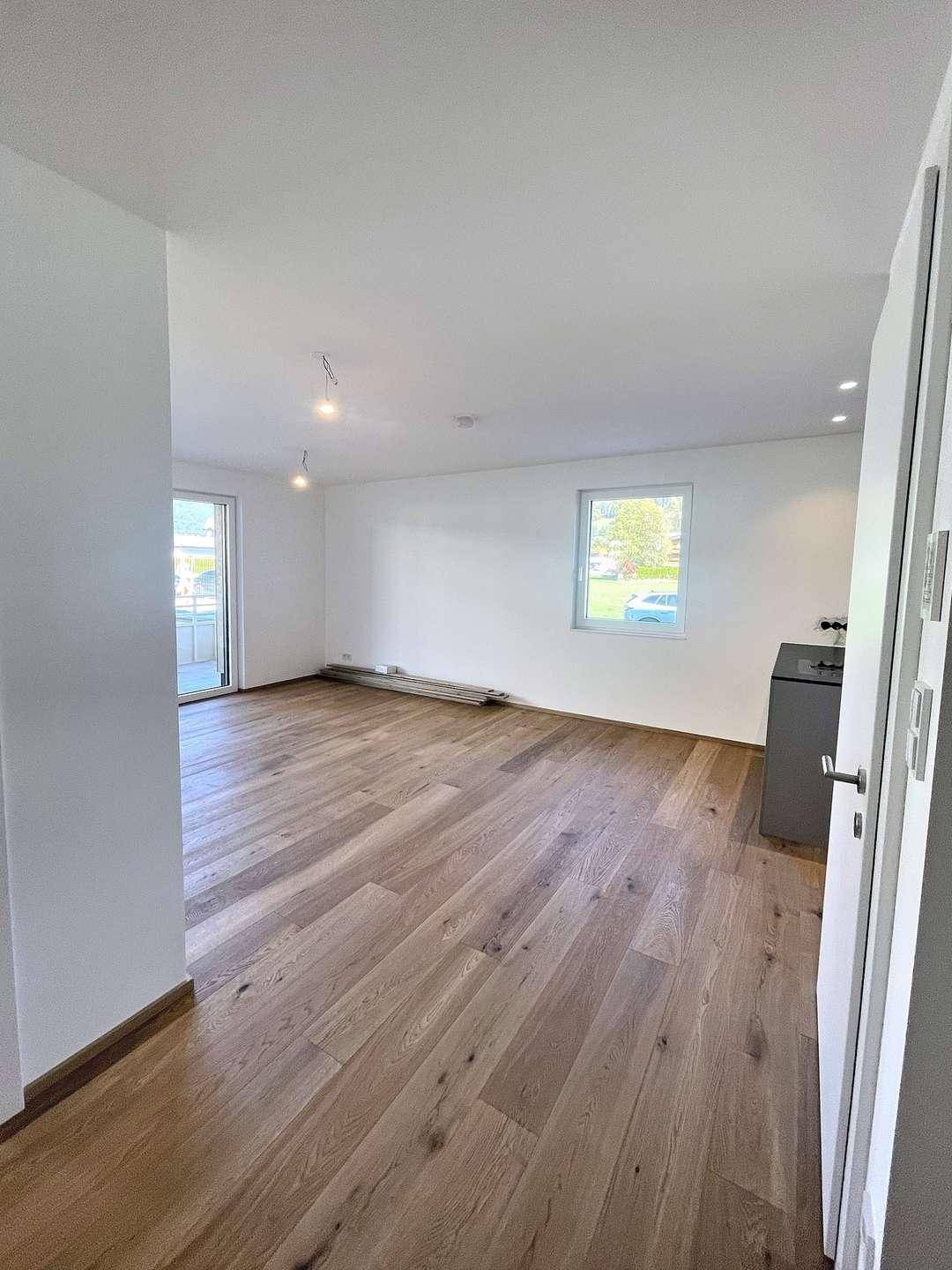 Heller Wohnbereich mit Holzboden und Fenster, der viel Tageslicht hereinlässt.
