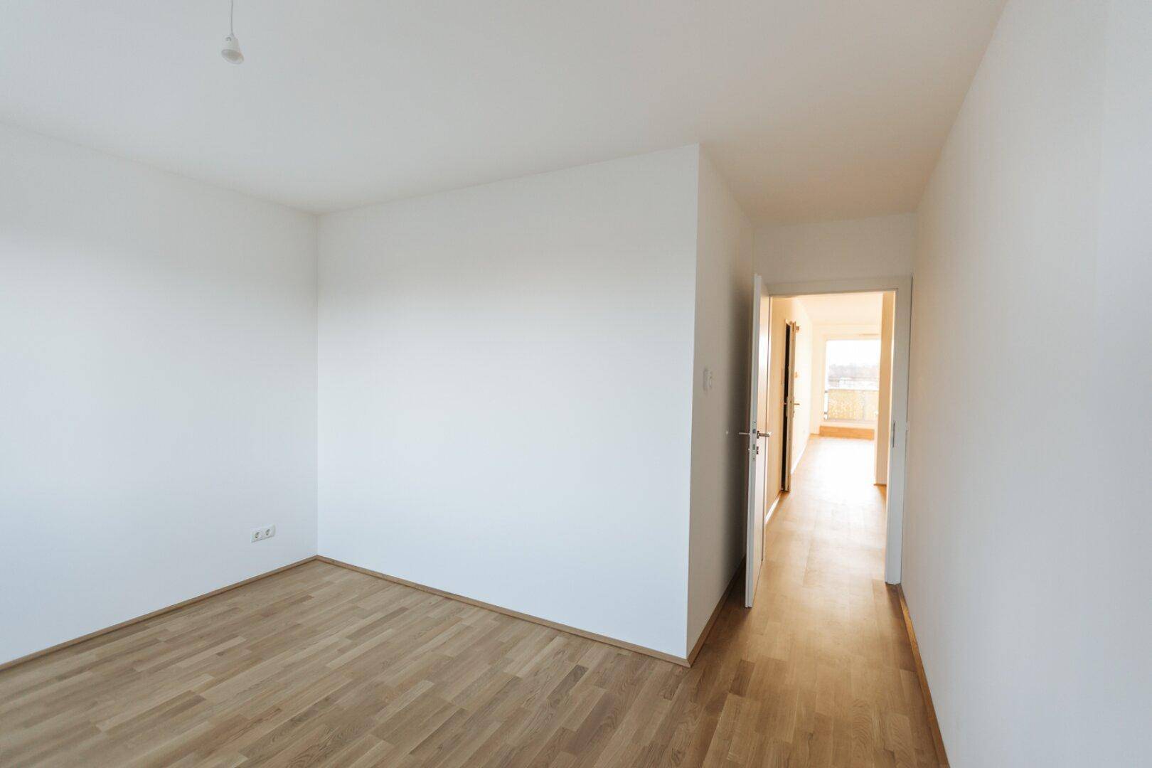Helles Zimmer mit Parkettboden und weiß gestrichenen Wänden, bereit zur Einrichtung.