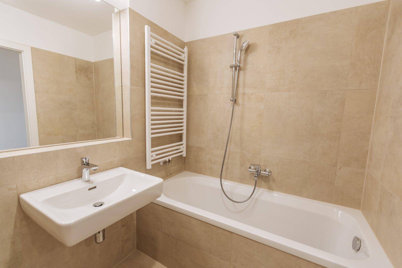 Modernes Badezimmer mit Badewanne, Waschbecken und beheiztem Handtuchhalter.