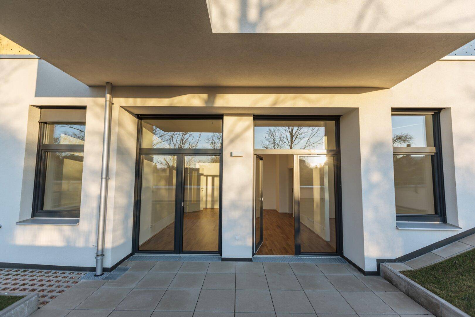 Erdgeschoss-Terrasse mit großen Glasfronten, die viel Licht in die Innenräume lassen.