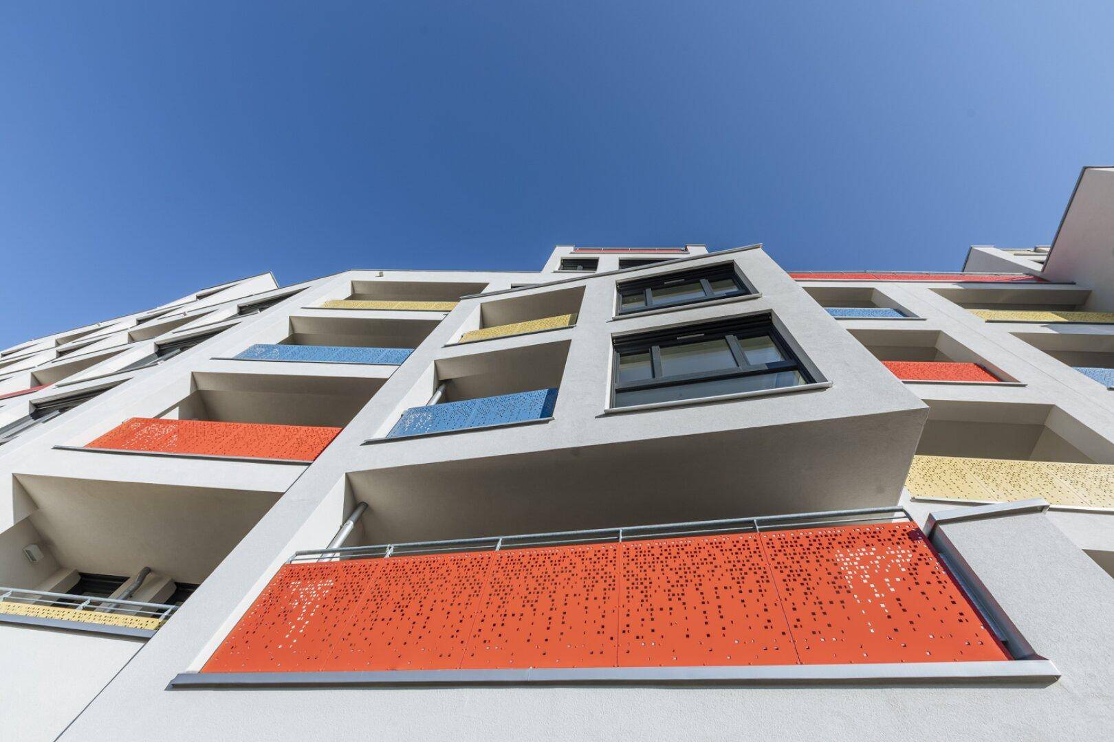 Moderne Wohnanlage mit farbenfrohen Balkonen und zeitgenössischer Architektur.