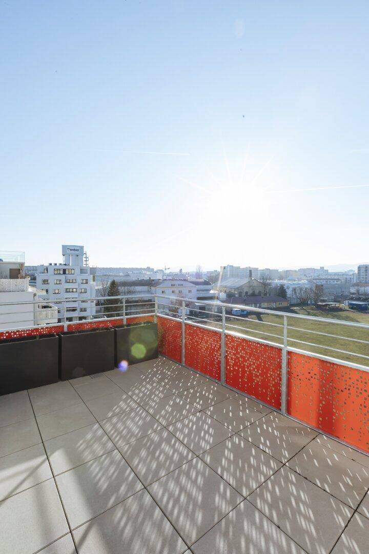 Geräumige Terrasse mit Fliesenboden und einem modernen Geländer, das einen weiten Blick bietet.