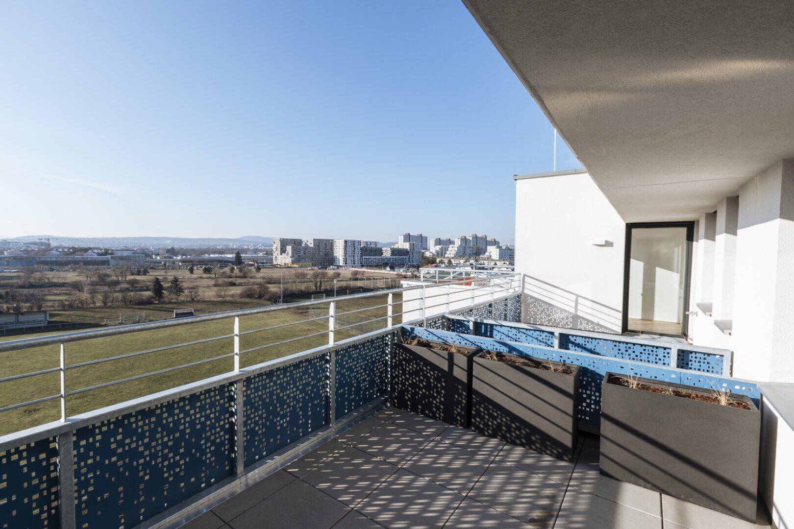 Großer Balkon mit Fliesenboden und modernen, perforierten Geländern, bietet einen Panoramablick.
