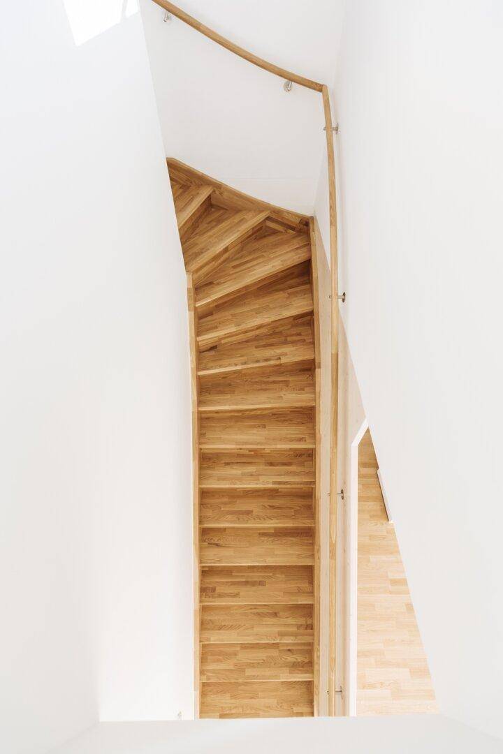 Elegante Holztreppe mit geschwungenem Handlauf, die die verschiedenen Ebenen verbindet.