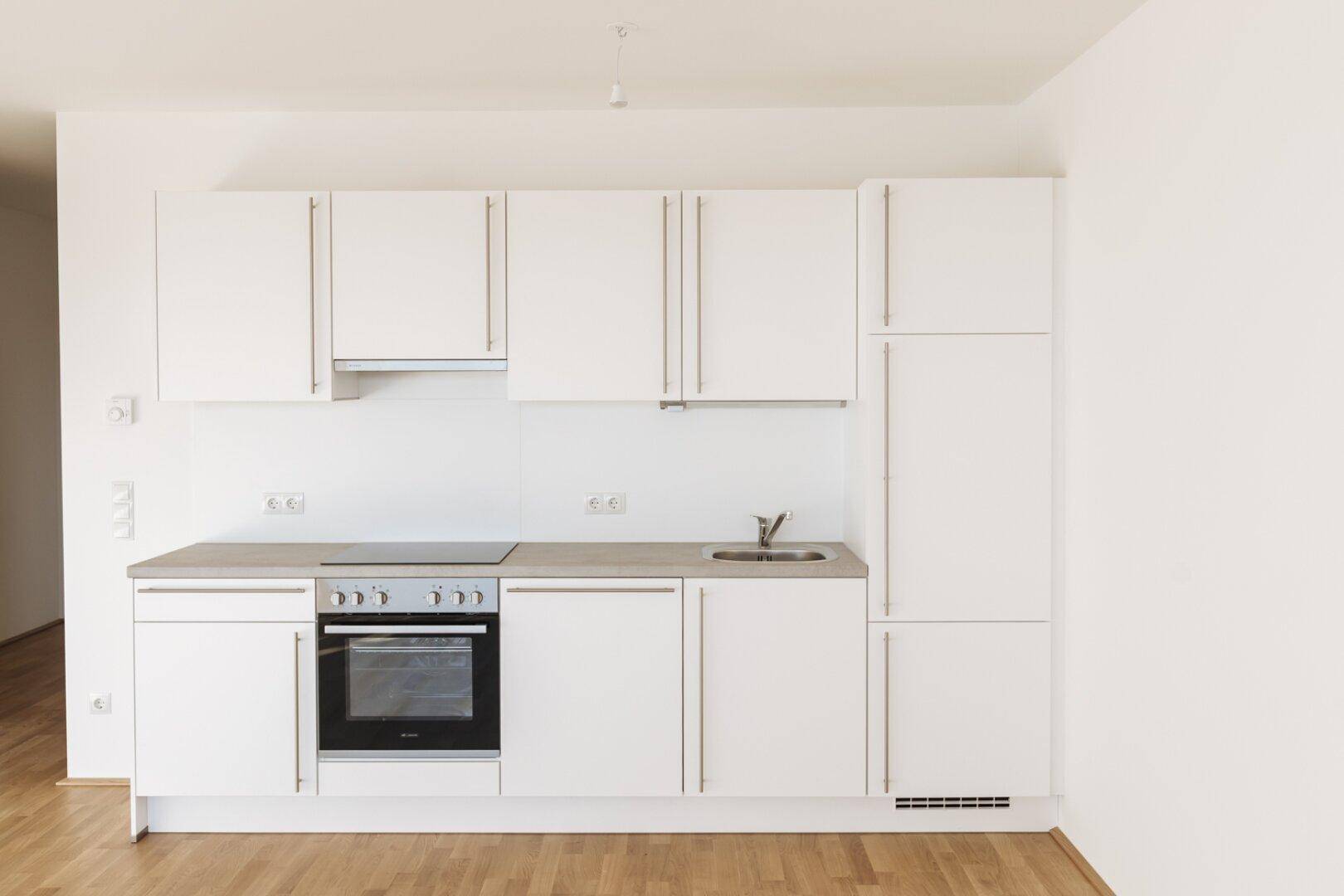 Detailansicht der modernen weißen Einbauküche mit integriertem Backofen und Induktionskochfeld.