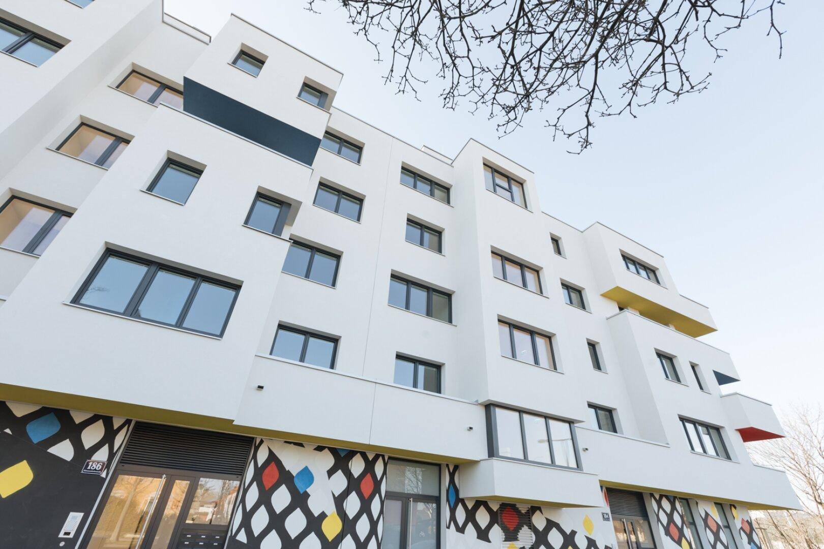 Moderne Gebäudefassade mit farbigen Akzenten und großen Fenstern.