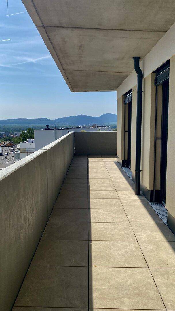 Langer Balkon mit Fliesenboden und weitem Blick auf die Stadt und die umliegende Landschaft.