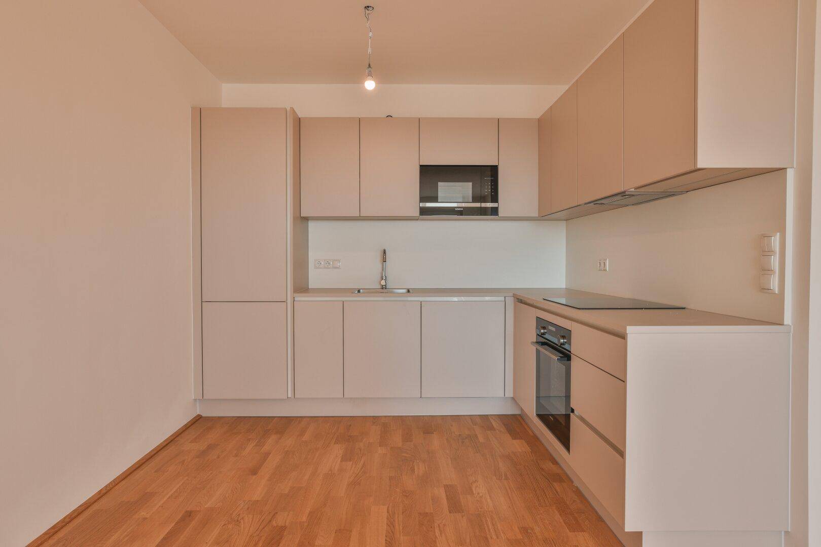 Neue, moderne Einbauküche mit hellen Fronten, integriertem Backofen und Induktionskochfeld.