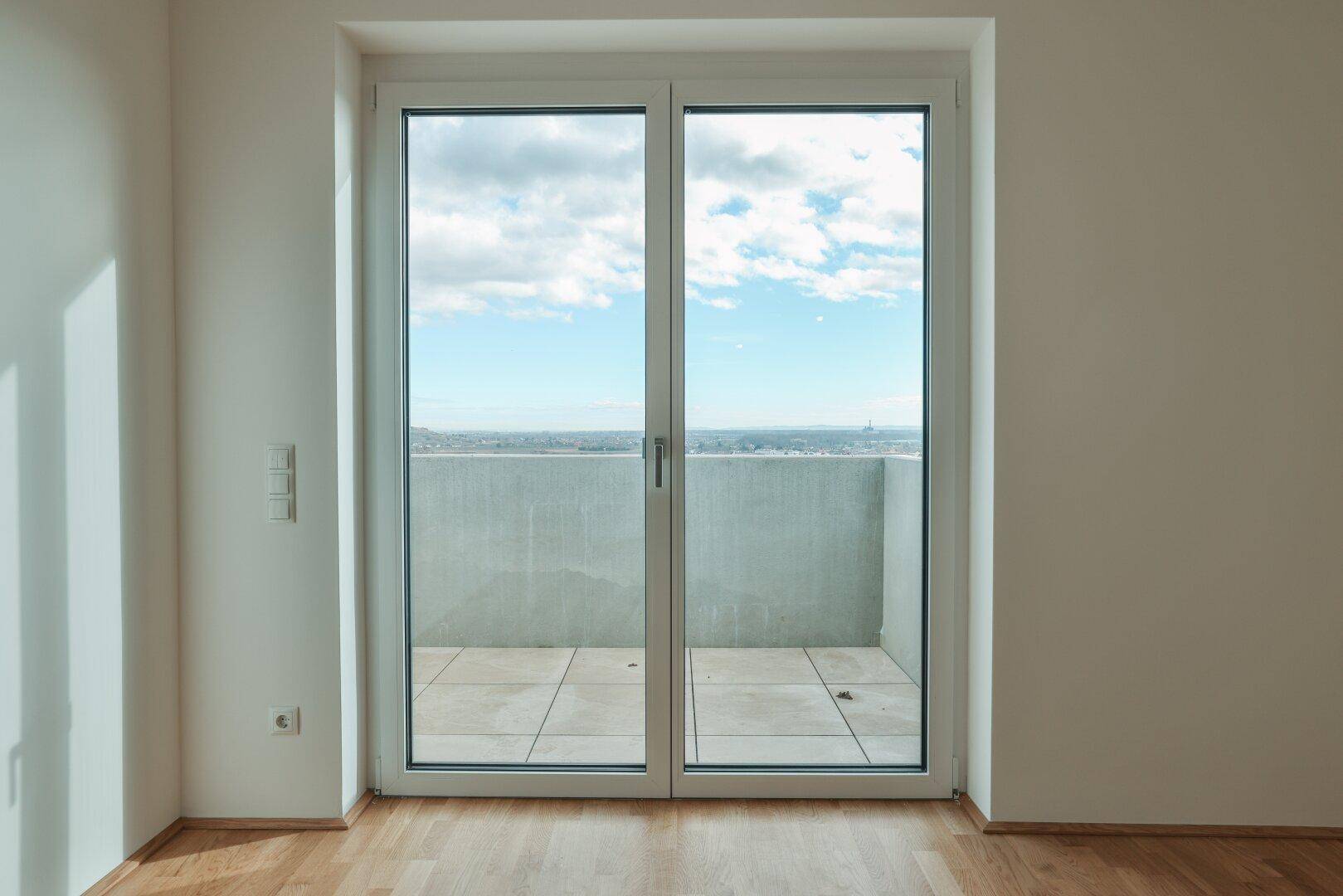 Große Balkontür im Wohnzimmer bietet Zugang zum Außenbereich und lässt viel Licht herein.