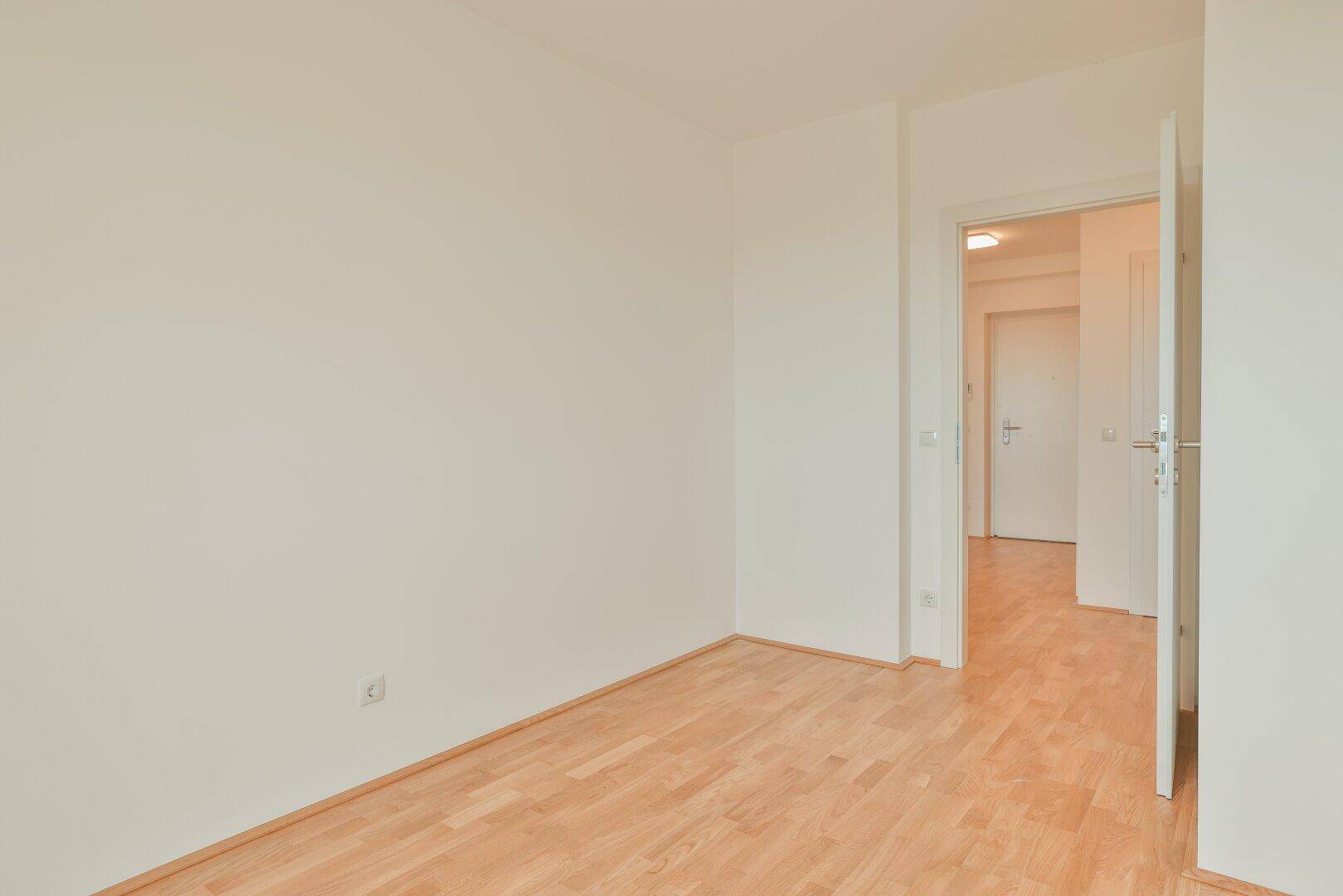Geräumiges Schlafzimmer mit Parkettboden und weiß gestrichenen Wänden, bereit zur Einrichtung.