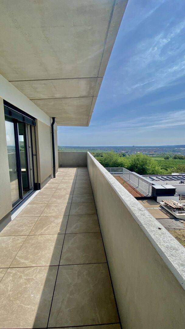 Geräumiger Balkon mit Fliesenboden und Panoramablick über die grüne Landschaft.