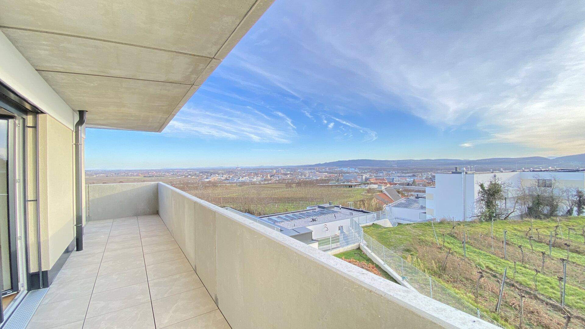 Geräumiger Balkon mit Fliesenboden und weitem Blick über die Weinberge und Stadt.