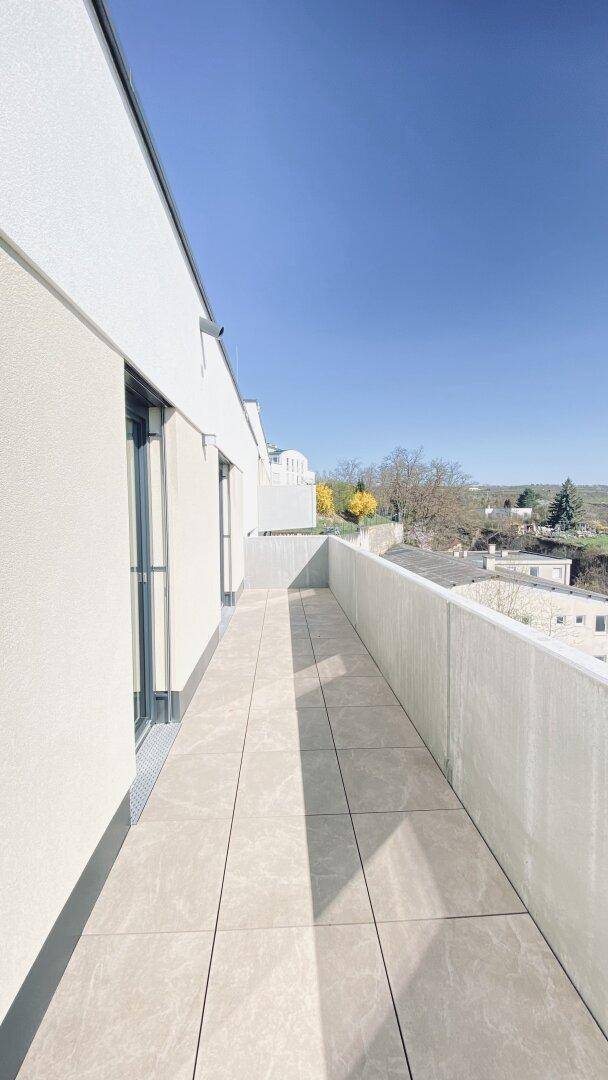 Sonniger Balkon mit Fliesenboden und moderner Brüstung, bietet einen weiten Ausblick.