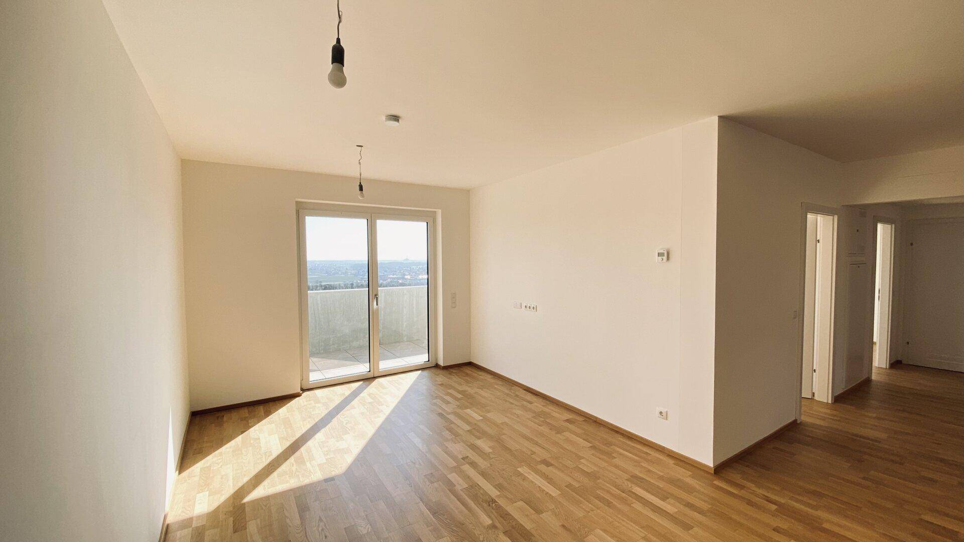 Geräumiger Wohnbereich mit viel Tageslicht, Parkettboden und direktem Zugang zu einem sonnigen Außenbereich.