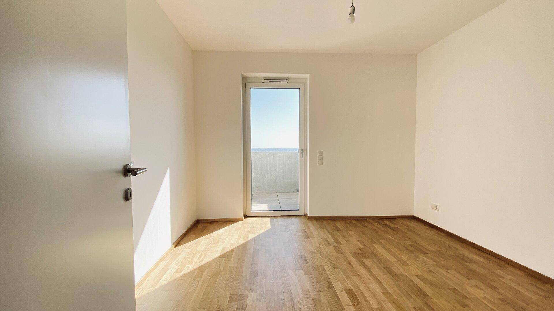 Freundliches Schlafzimmer mit Holzboden und Zugang zu einem Außenbereich, ideal für ruhige Morgenstunden.