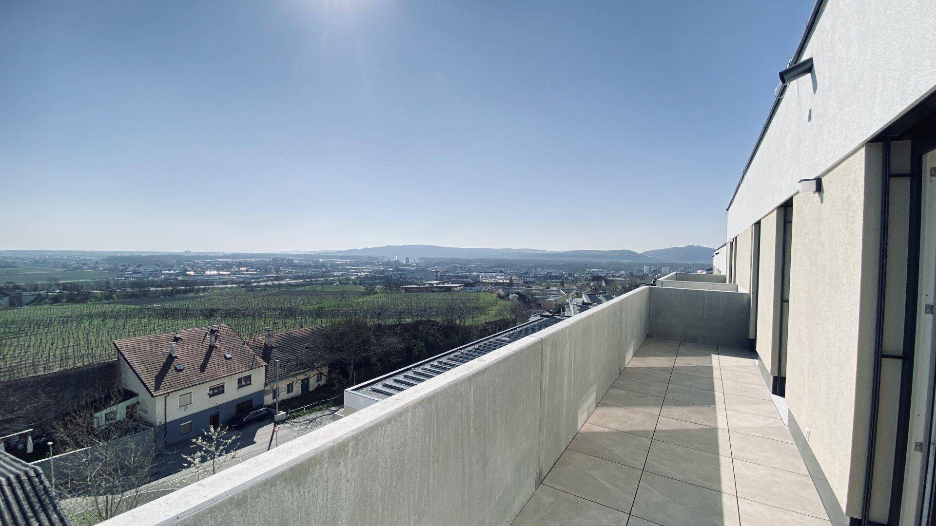 Weitläufige Sonnenterrasse mit Fliesenboden und Panoramablick über die umliegende Landschaft und Weinberge.