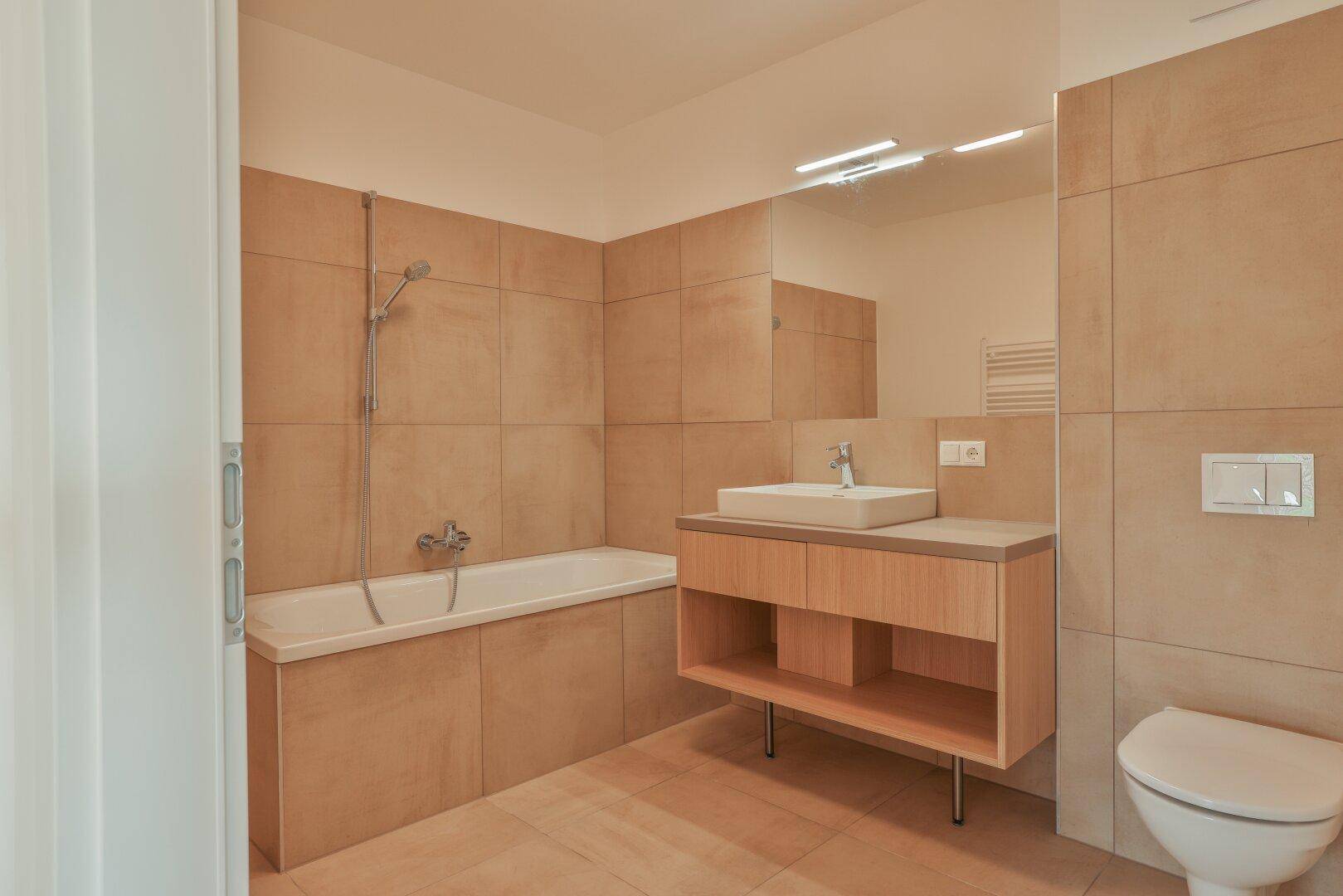 Zeitgemäßes Badezimmer mit Badewanne, Duschfunktion und einem eleganten Waschbeckenunterschrank.
