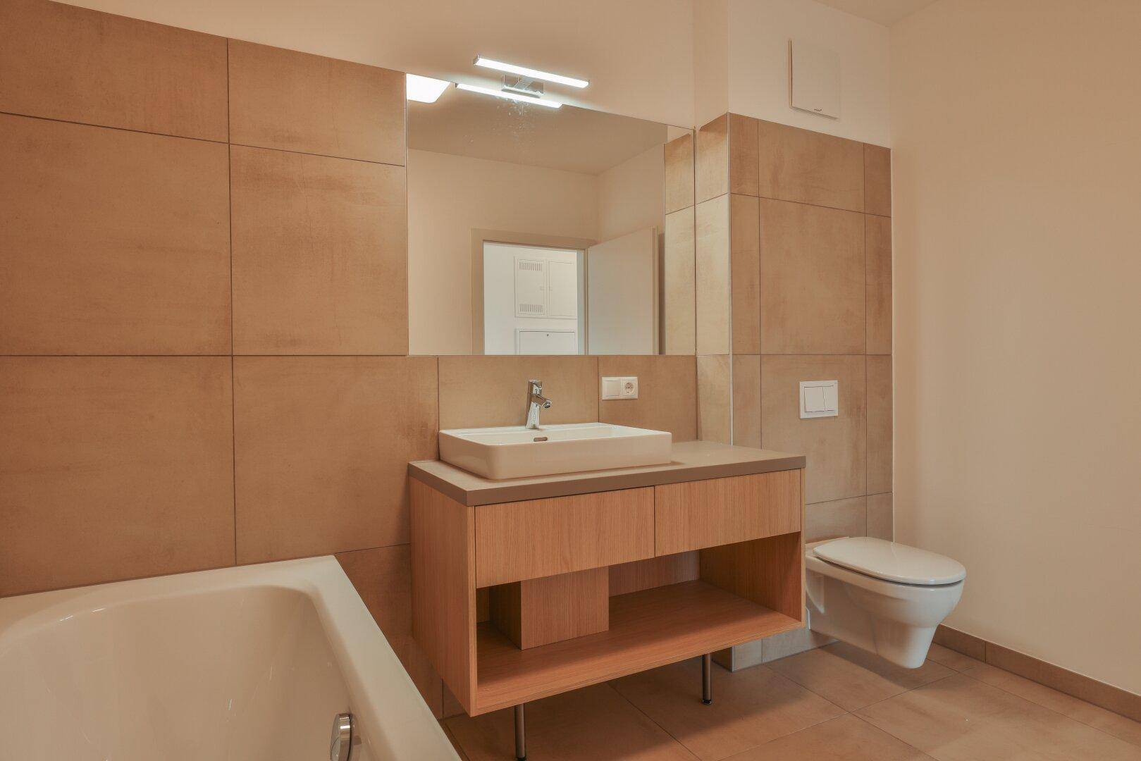 Modernes Badezimmer mit beigefarbenen Fliesen, einem Waschbeckenunterschrank und einer Badewanne.