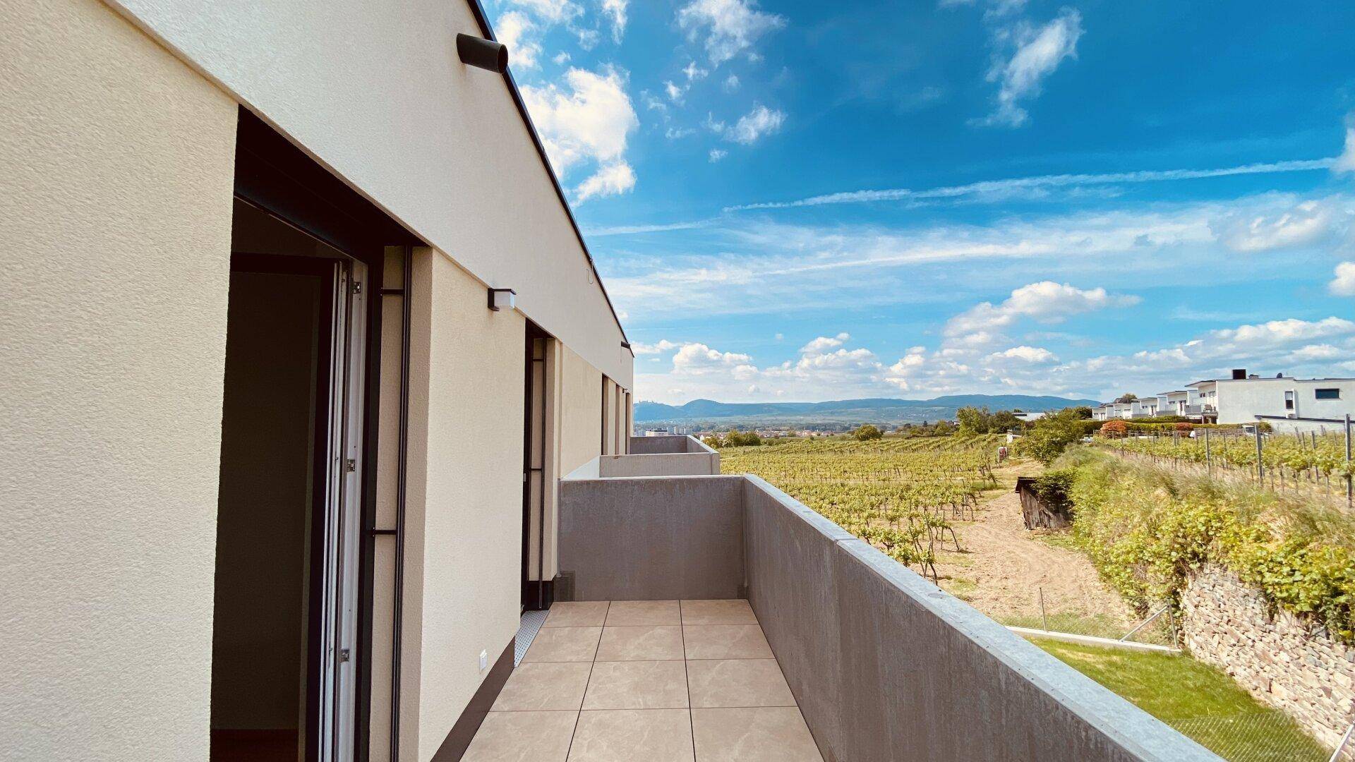 Geräumiger Balkon mit Fliesenboden und weitem Blick über Weinberge und die umliegende Landschaft.