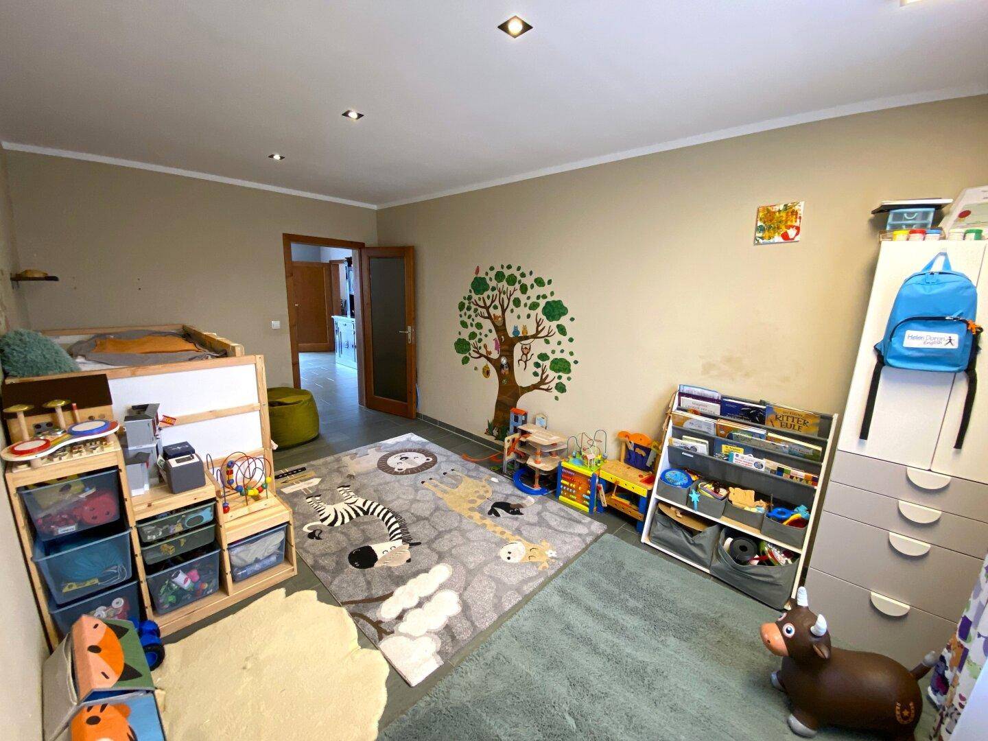 Kinderzimmer mit Spielzeug, Teppich und Wanddekoration, ideal für kleine Kinder.