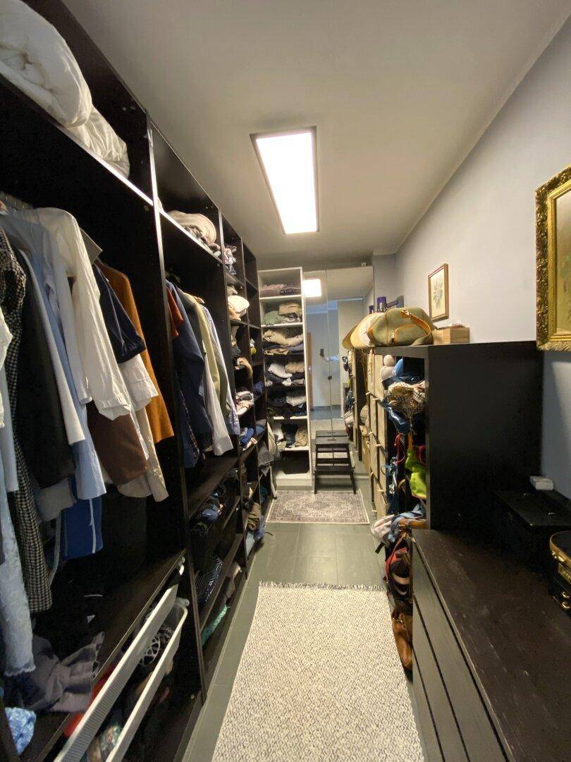Geräumiger begehbarer Kleiderschrank mit vielen Regalen und Aufbewahrungsmöglichkeiten.