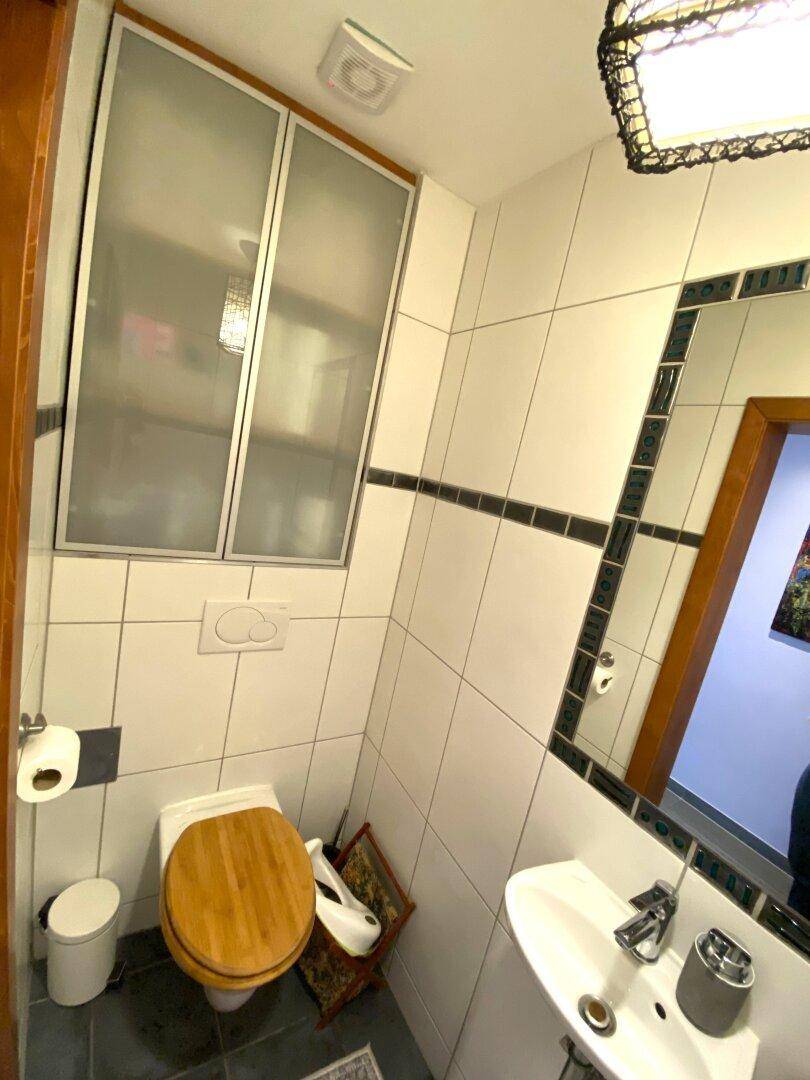 Kleines Gäste-WC mit Waschbecken, Toilette und Fliesen an Wänden und Boden.