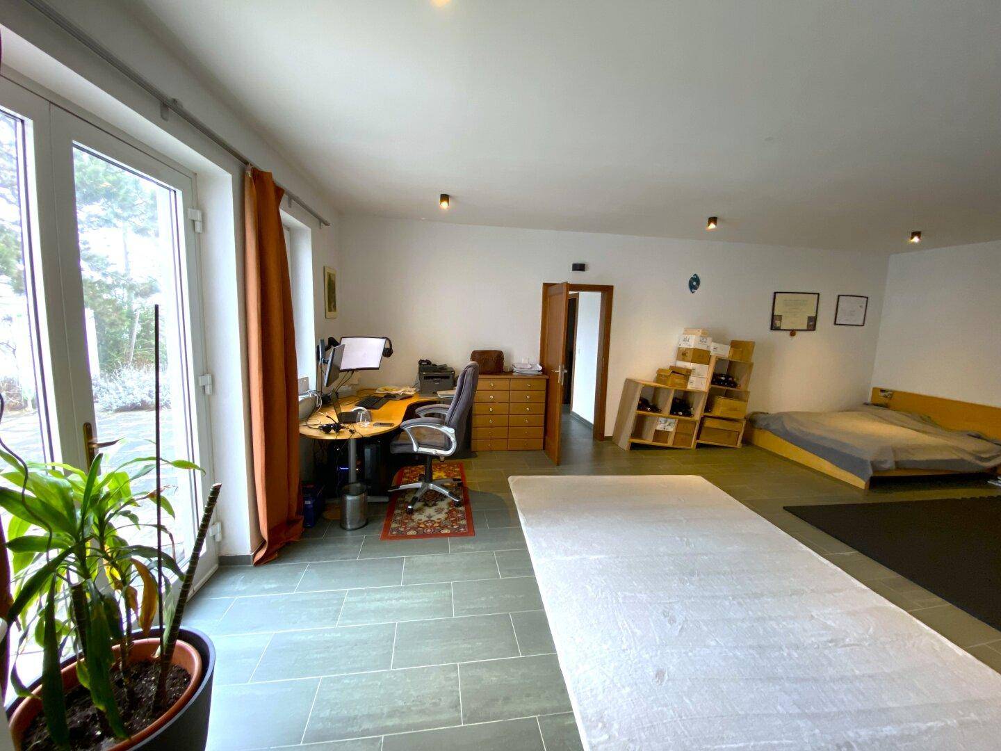 Geräumiges Zimmer mit Arbeitsbereich und Zugang zum Garten durch große Türen.
