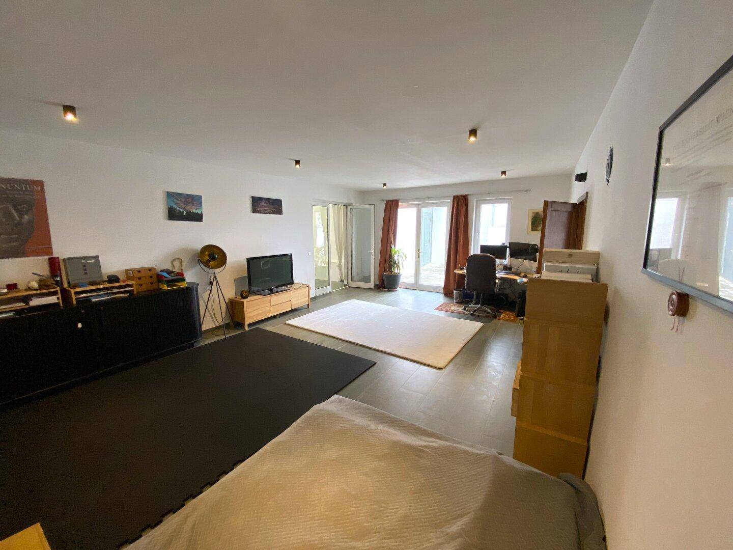 Großes Zimmer mit Arbeitsbereich, Schlafgelegenheit und Blick auf den Garten.