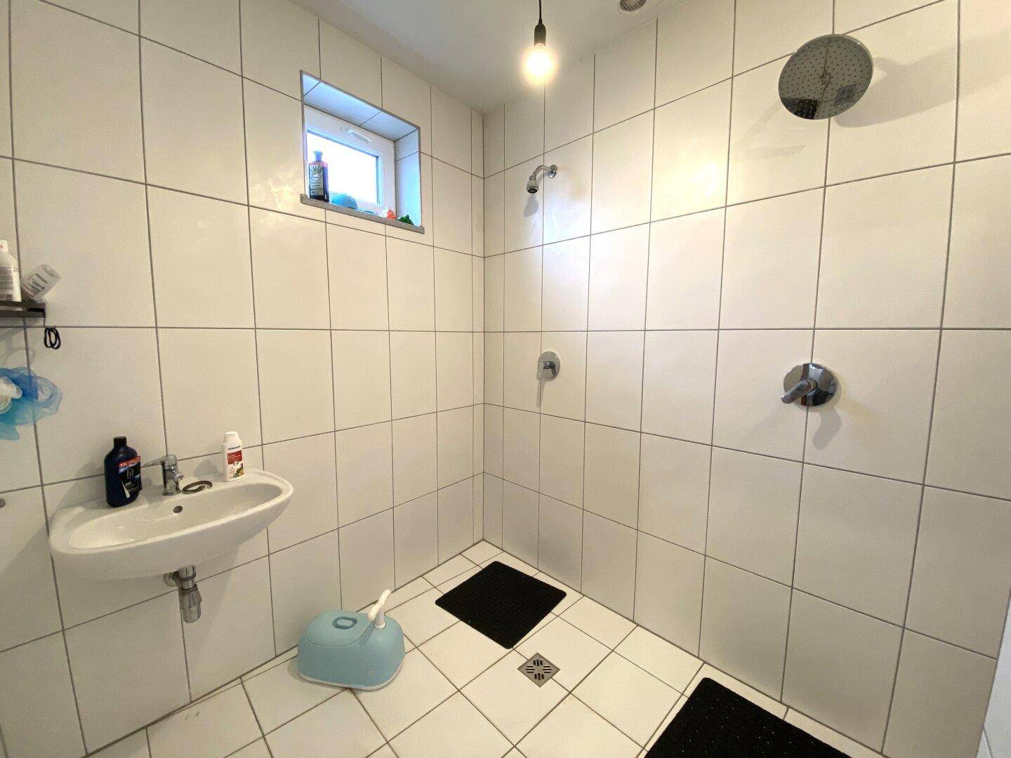 Geräumiges Badezimmer mit großer Duschfläche, Waschbecken und Fenster.