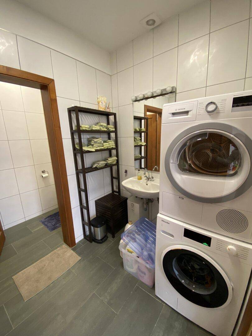 Praktischer Hauswirtschaftsraum mit Waschmaschine, Trockner und Stauraum.