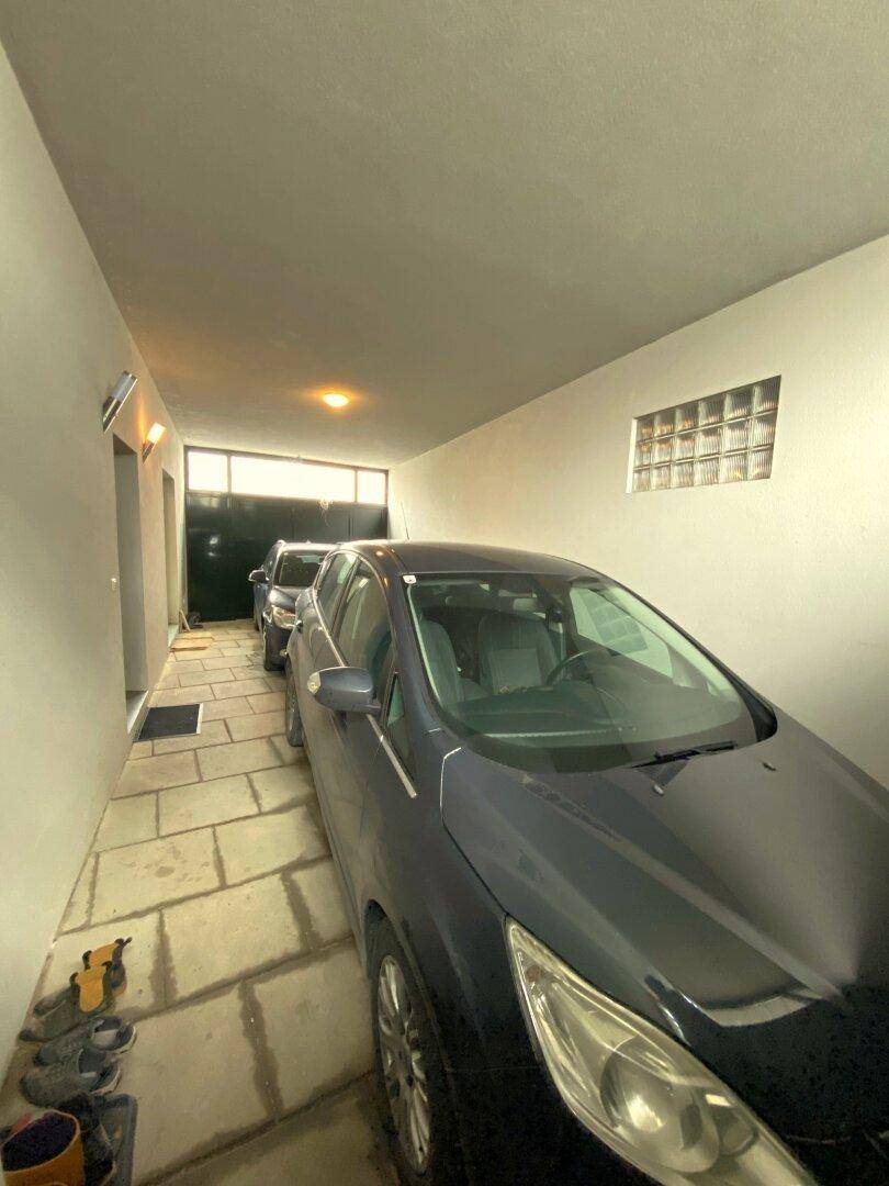 Lange Garage mit zwei geparkten Autos und einem Fenster mit Glasbausteinen.