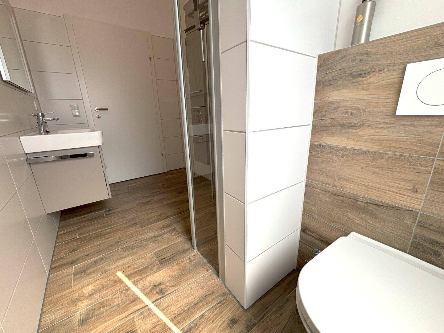 Modernes Badezimmer mit Waschtisch, Toilette und Duschbereich.