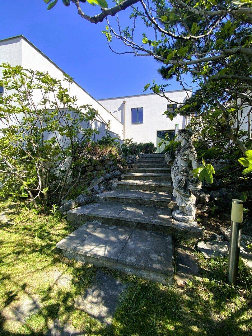 Heller Eingangsbereich des modernen Hauses mit Steintreppe und dekorativer Statue.