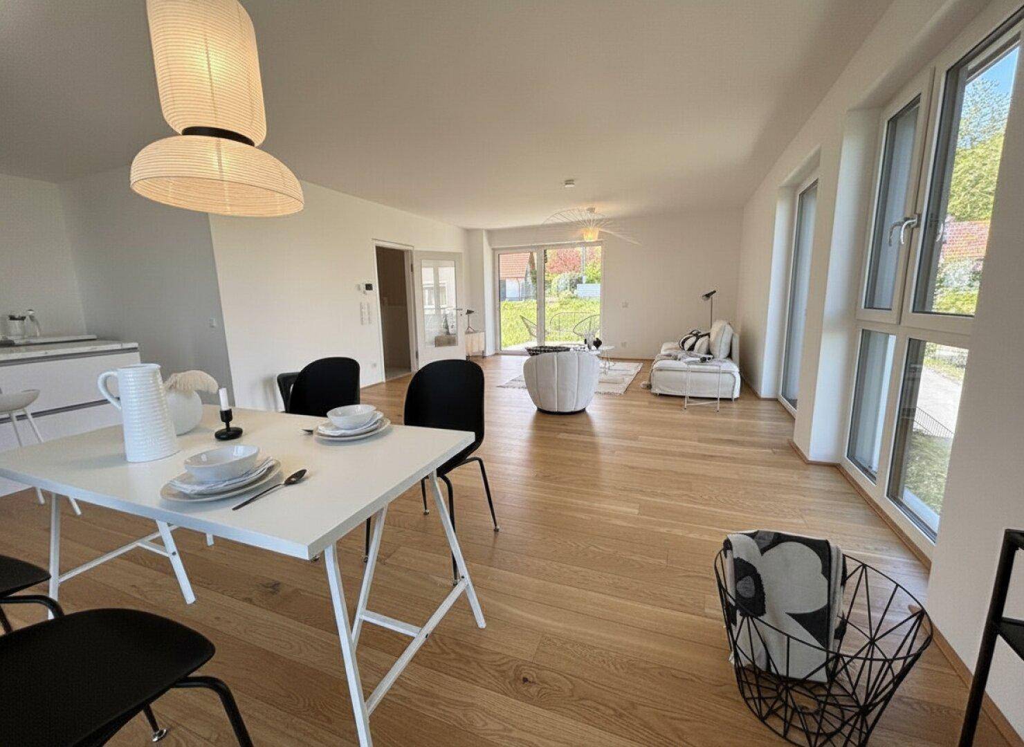 Offener Wohn-Essbereich mit integrierter Küche, Holzboden und Zugang zum Gartenbereich.