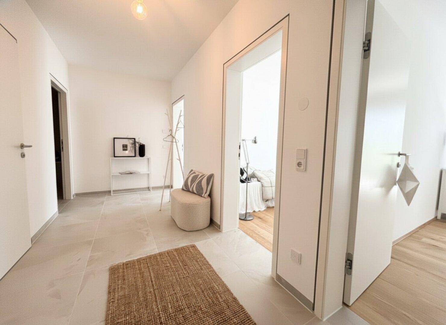 Heller Flur mit modernen Fliesen, weiß gestrichenen Wänden und minimalistischer Dekoration.