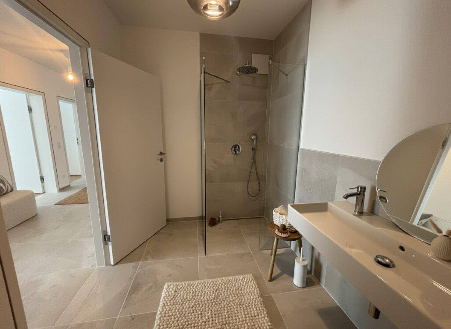 Modernes Badezimmer mit begehbarer Dusche, Einzelwaschbecken und hellen Fliesen.