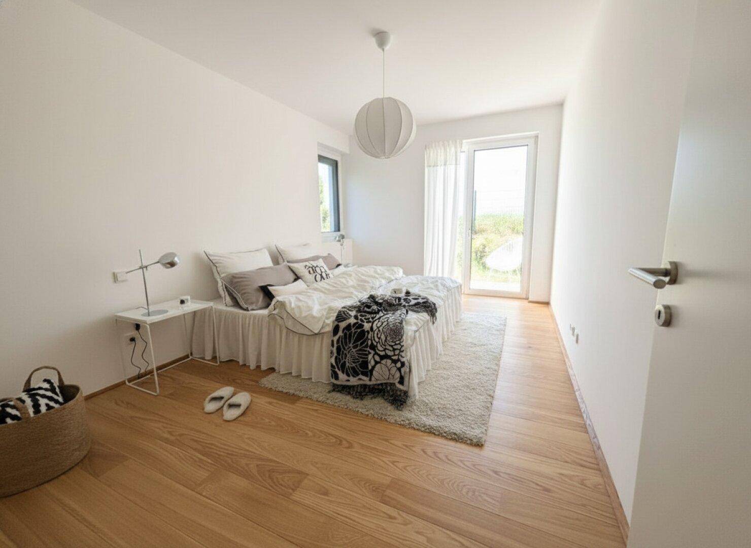 Geräumiges Schlafzimmer mit Holzboden, Doppelbett und direktem Zugang zu einem Außenbereich.