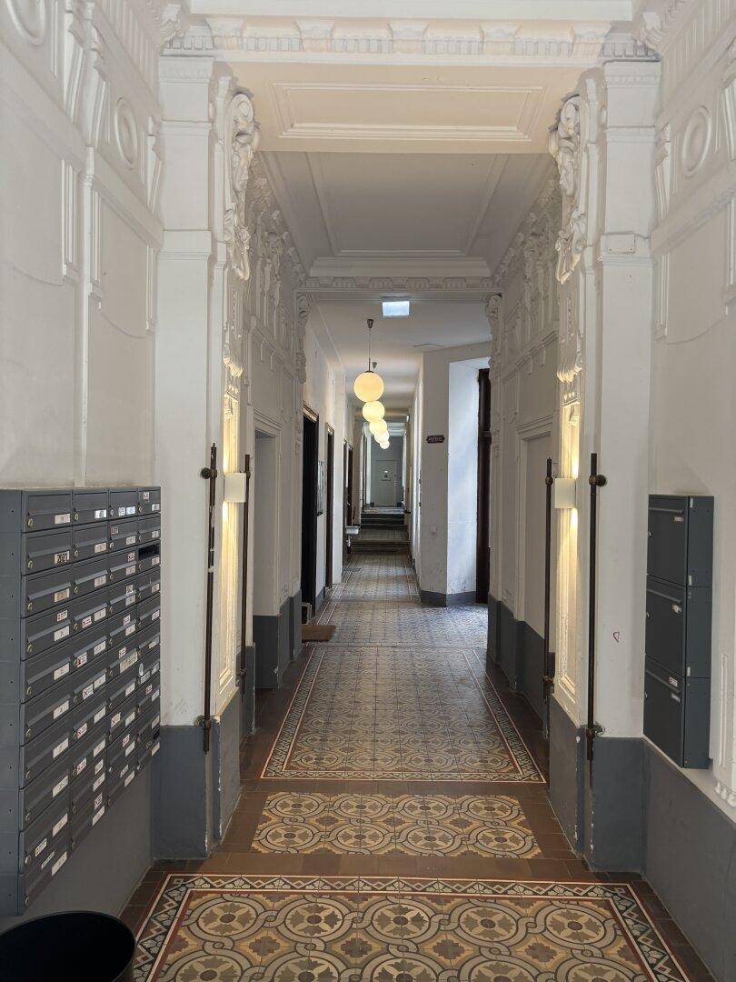Prunkvoller Gemeinschaftsflur eines Altbaus mit Stuckdecken, historischen Fliesen und Briefkästen.