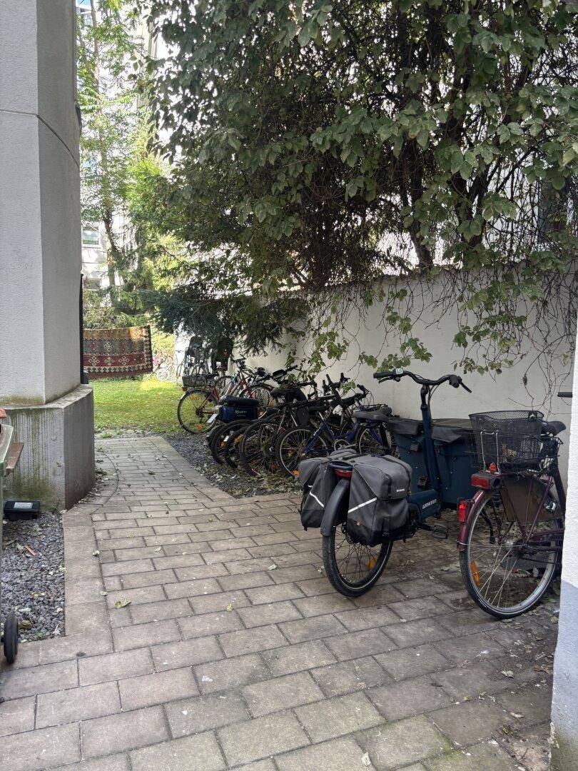 Grüner Außenbereich mit Fahrradabstellplätzen und Bäumen, ideal für Bewohner.