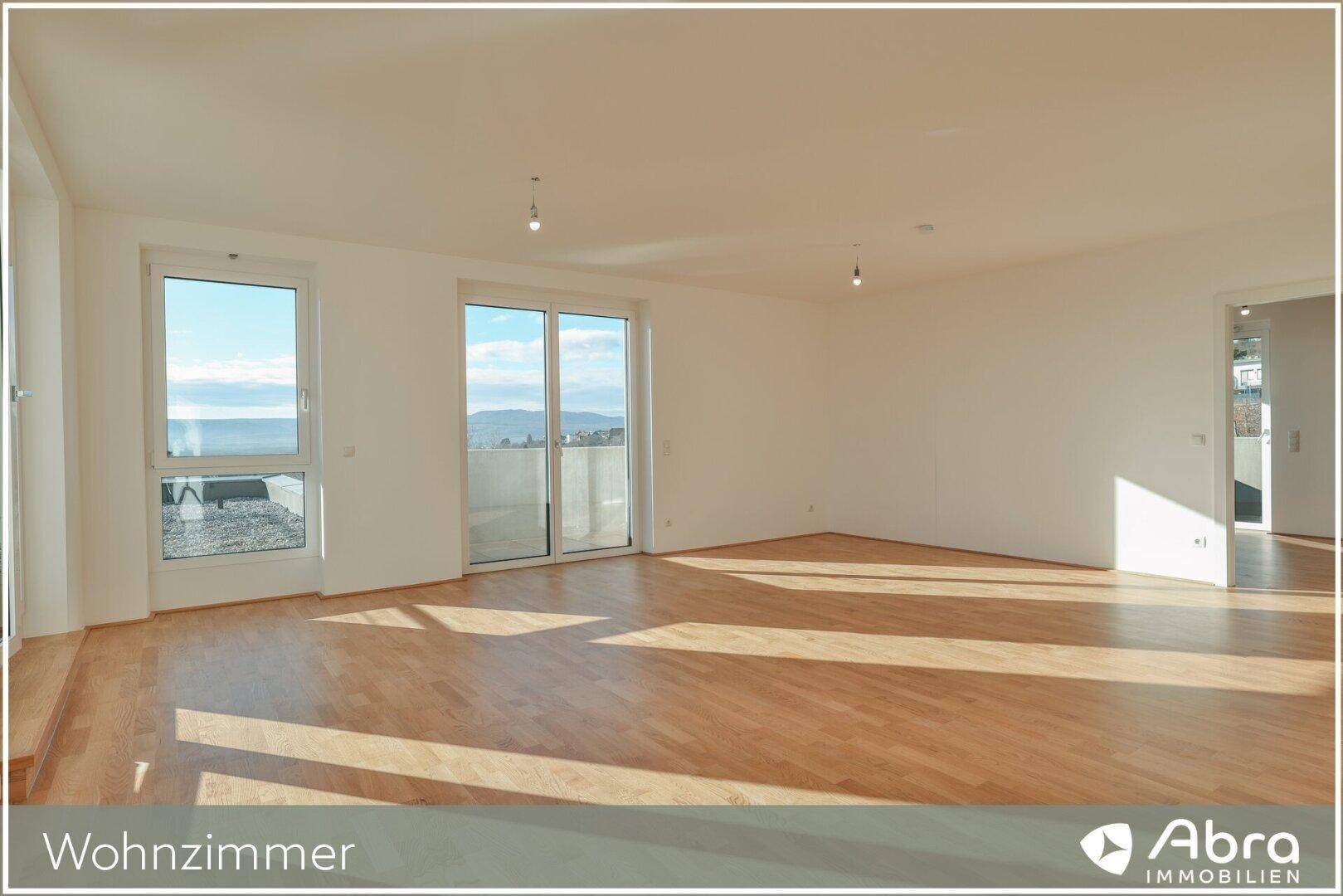 Großzügiges Wohnzimmer mit hellem Parkettboden und weitem Blick durch die großen Fensterfronten.