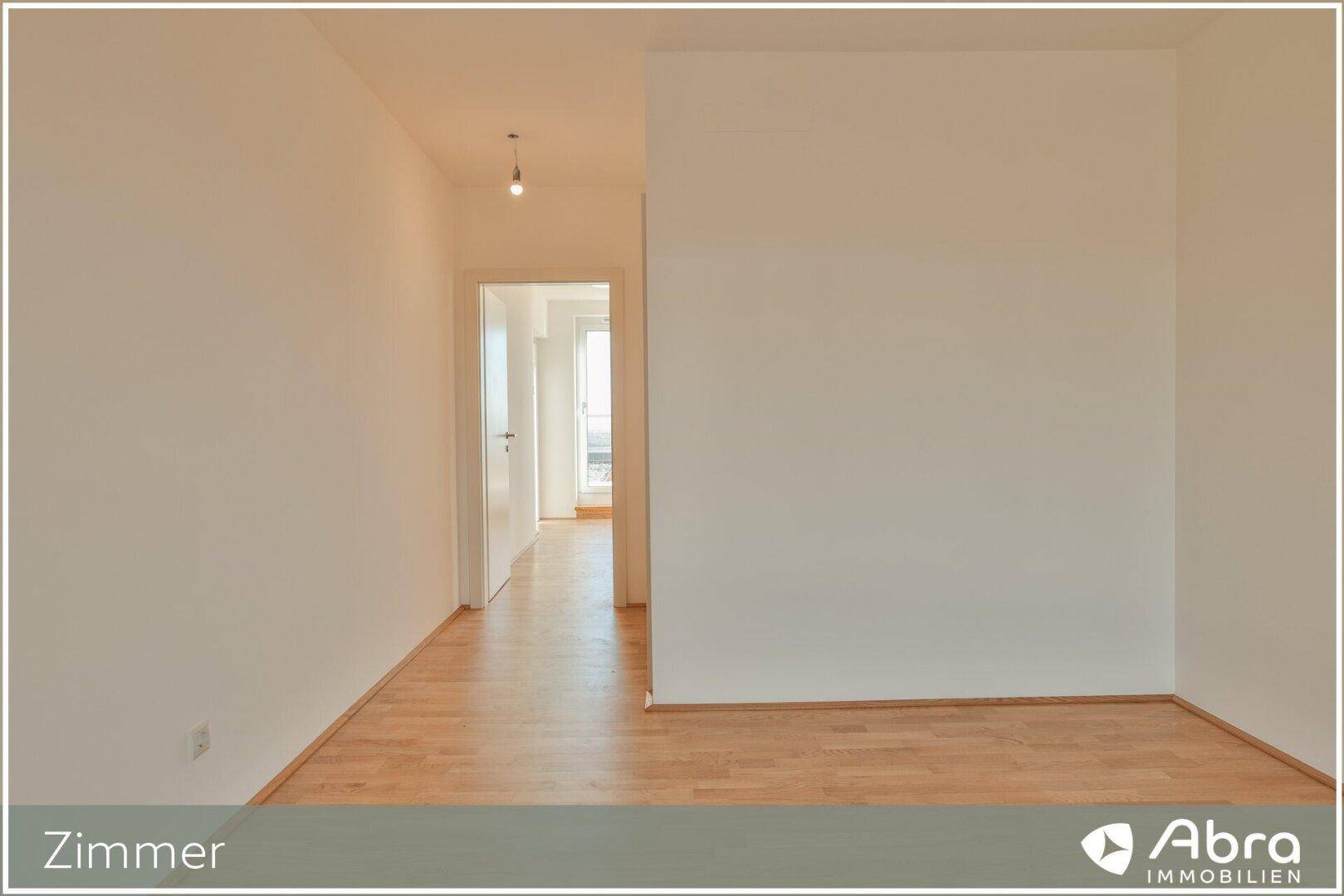 Geräumiges Zimmer mit hellem Parkettboden und Zugang zu einem Flur, ideal für Schlaf- oder Arbeitszimmer.