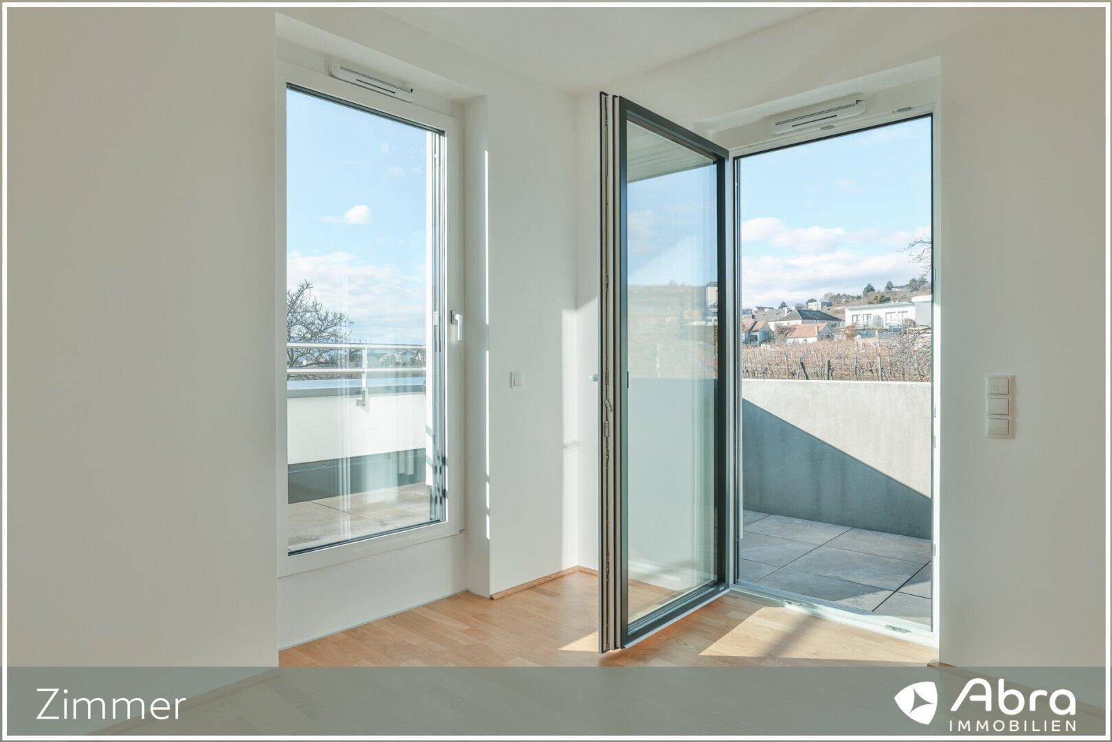 Helles Zimmer mit Parkettboden und großen Fenstern, die einen schönen Blick ins Grüne ermöglichen.