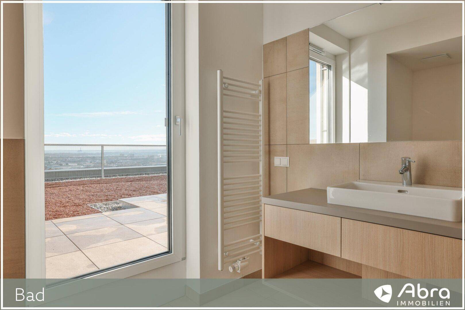 Helles Badezimmer mit Waschtisch, Spiegel, Handtuchheizkörper und großem Fenster mit schöner Aussicht.