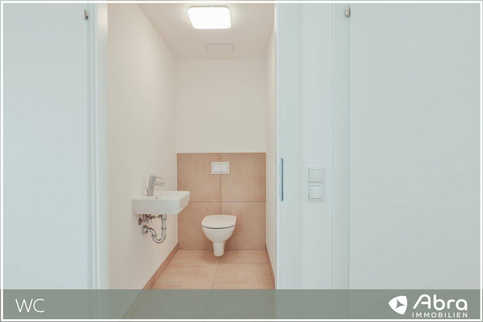 Separates Gäste-WC mit wandhängender Toilette und kleinem Handwaschbecken, modern gefliest.