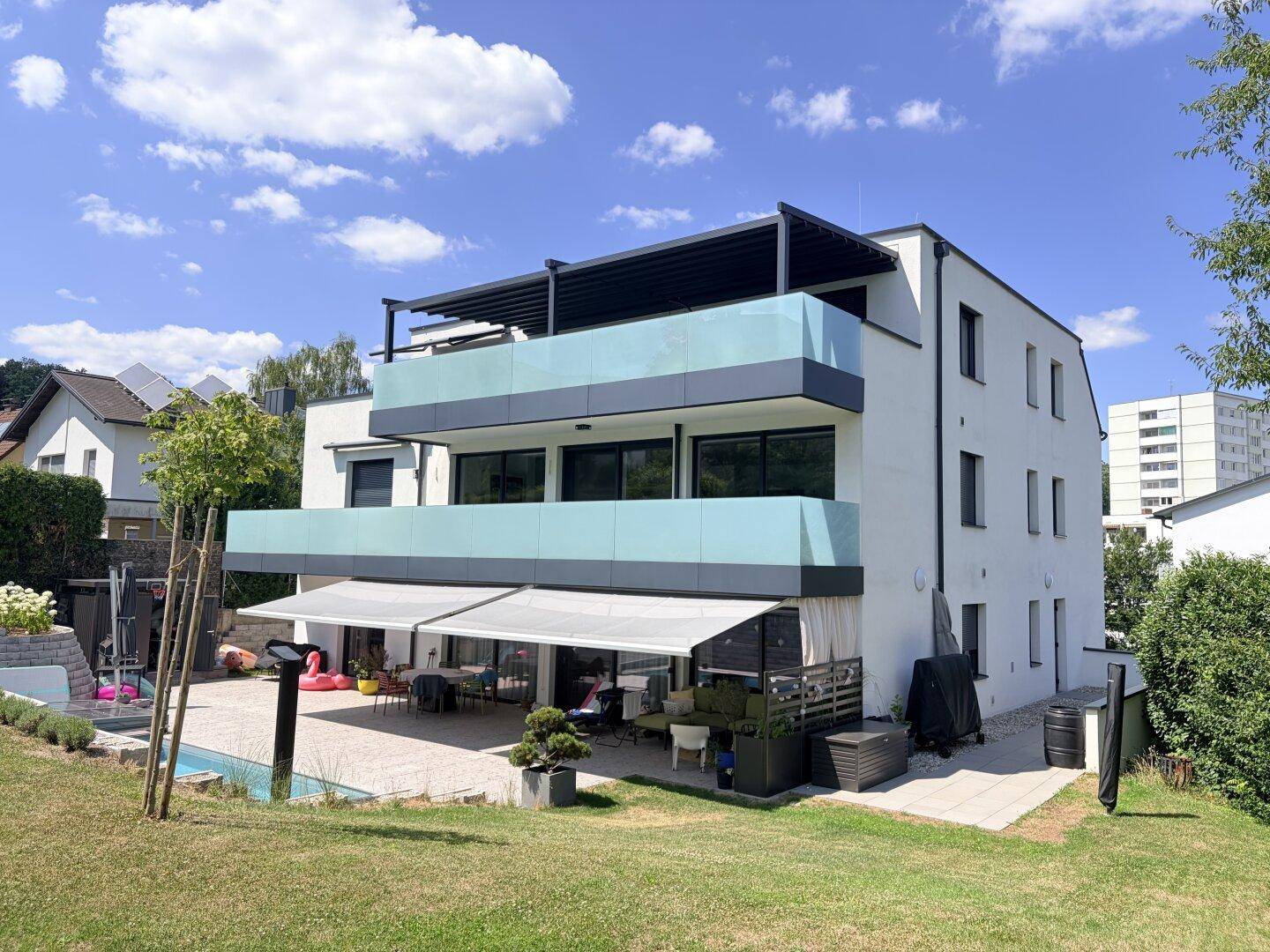 Modernes Gebäude mit mehreren Balkonen, Terrasse, Garten und kleinem Poolbereich.