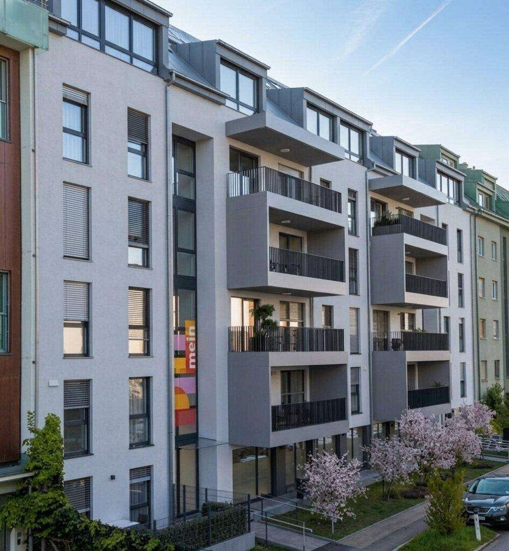 Neubau-Wohngebäude mit moderner Architektur, Balkonen und gepflegter Außenanlage.
