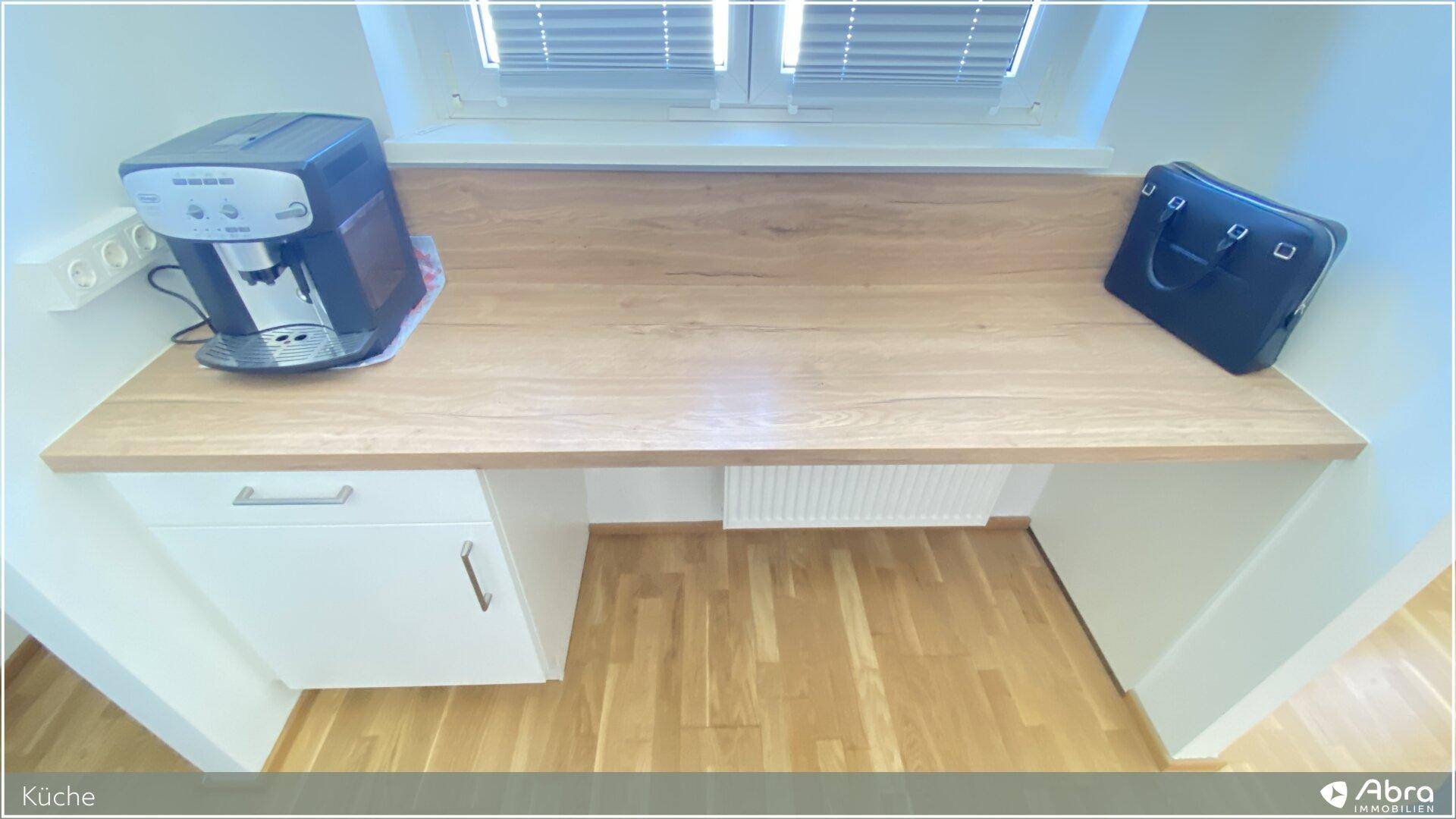 Küchenbereich mit Holz-Arbeitsplatte, Kaffeemaschine und Fenster für natürliches Licht.