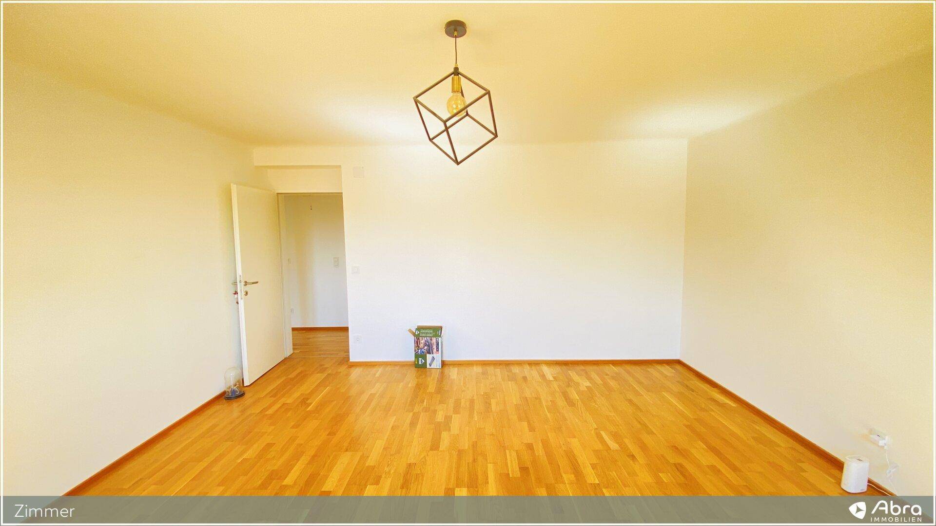 Helles Zimmer mit Holzboden und einer modernen Deckenleuchte, ideal für individuelle Gestaltung.